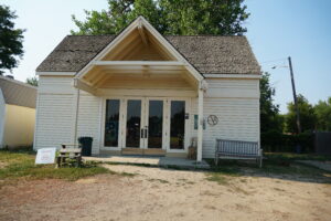 The Gate House, a white building with glass doors. There is a dirt path leading to a concrete porch.