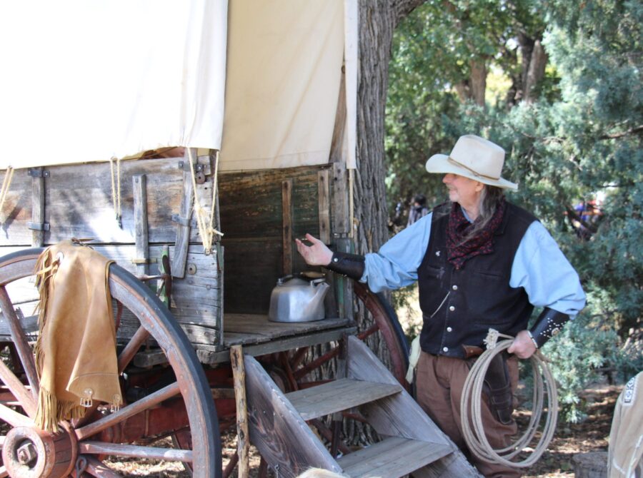 Volunteer in costume near a covered wagon outdoors