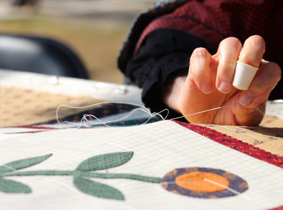 A person quilting with a thimble on their finger