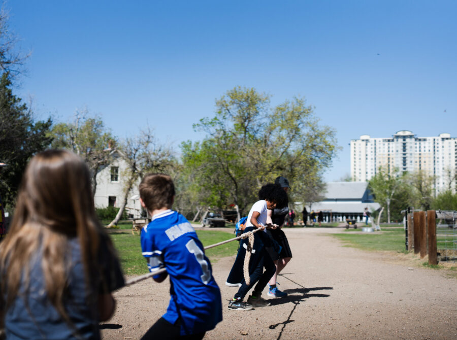 Children playing tug-of-war outside in a park.