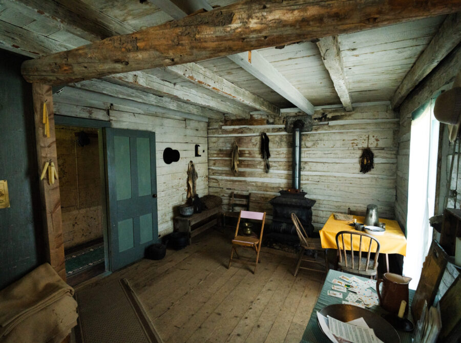 Rustic cabin interior with wood stove and table.