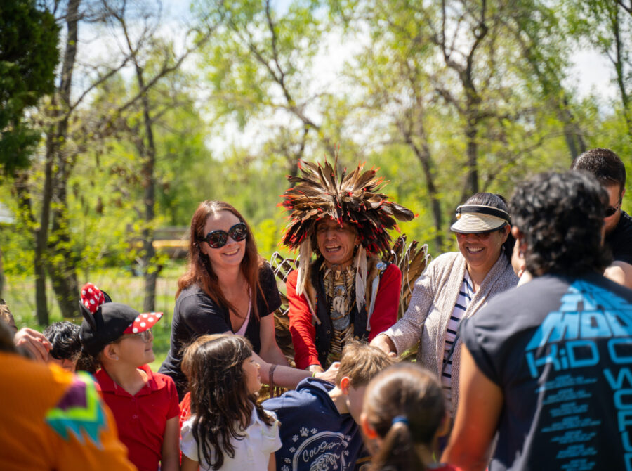 People gathered outdoors, one wearing a feathered headdress