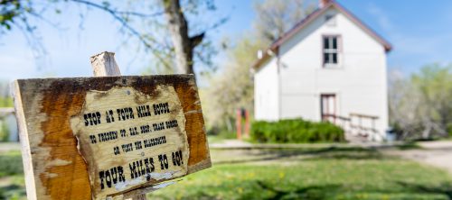 Rustic Four Mile House sign in front of reproduction school house
