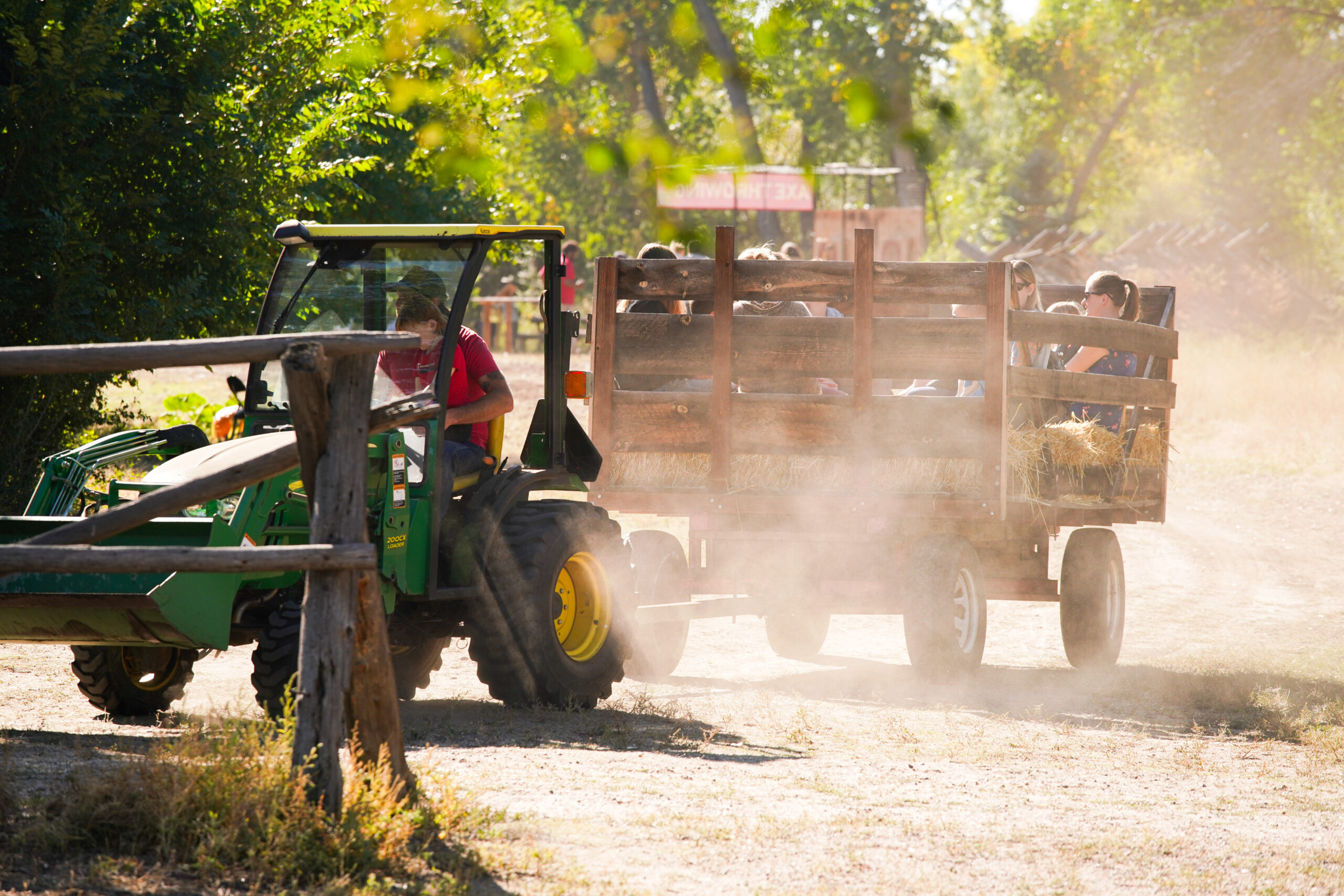 A tractor pulling a hay wagon with passengers.
