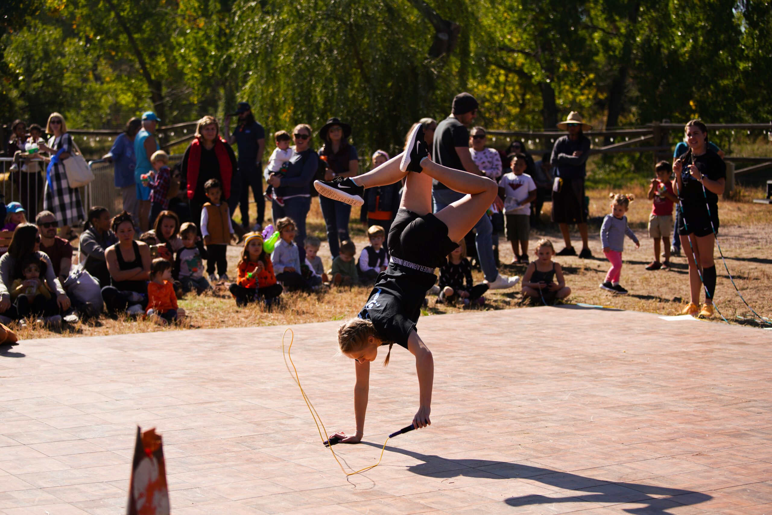 Person performing a handstand with jump rope, crowd watching