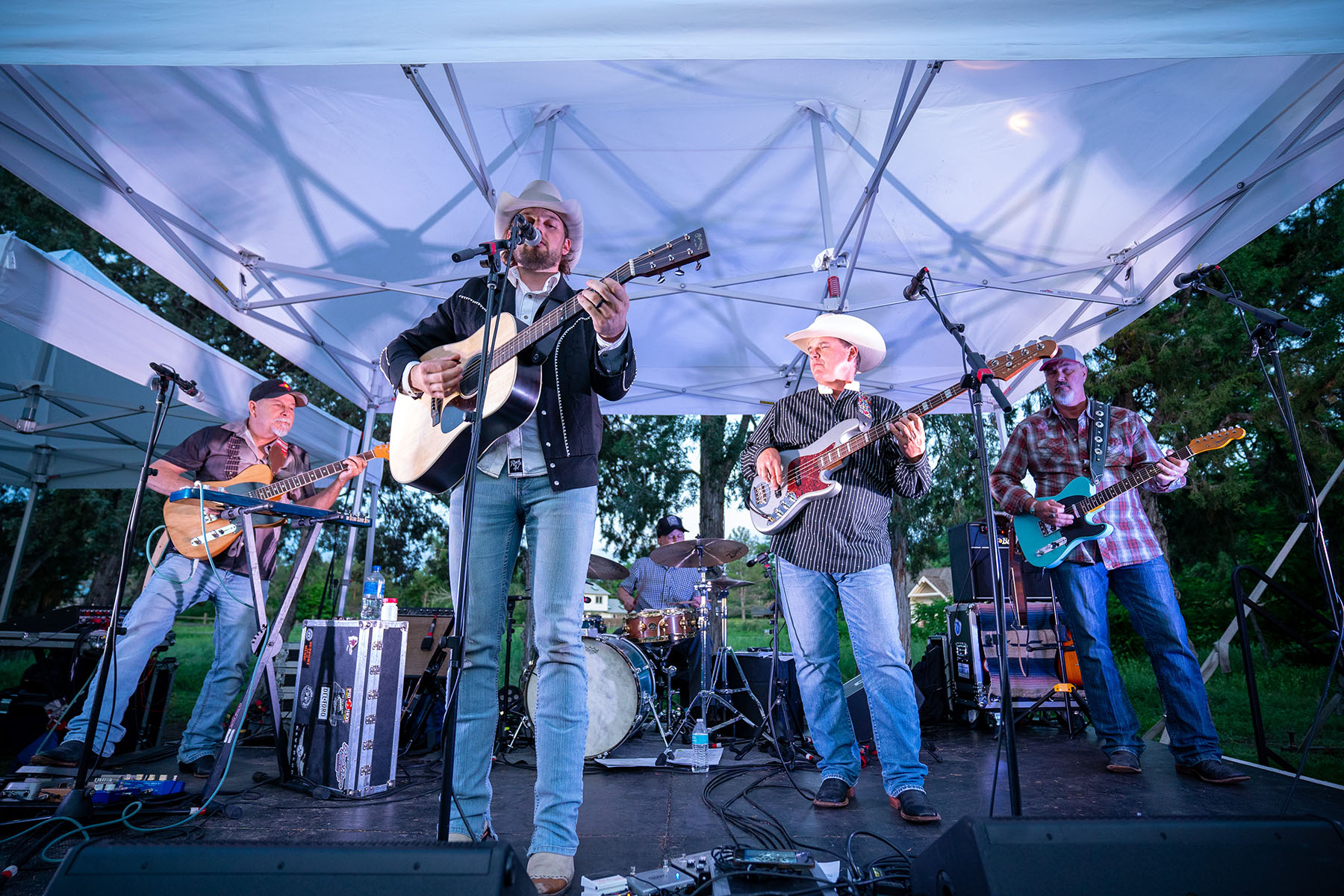 Band performing under a tent canopy outdoors.