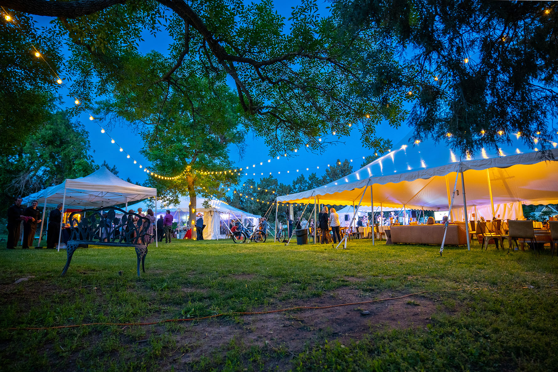Outdoor event with tents and string lights at dusk.