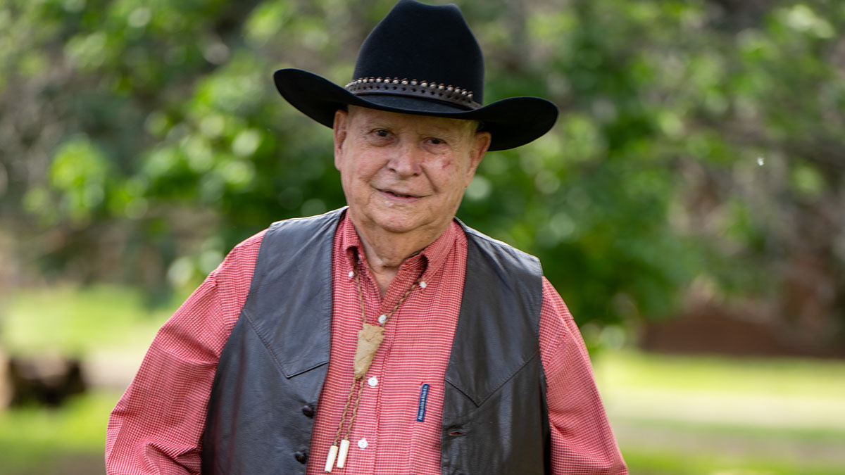 Elderly man in cowboy hat and vest outdoors
