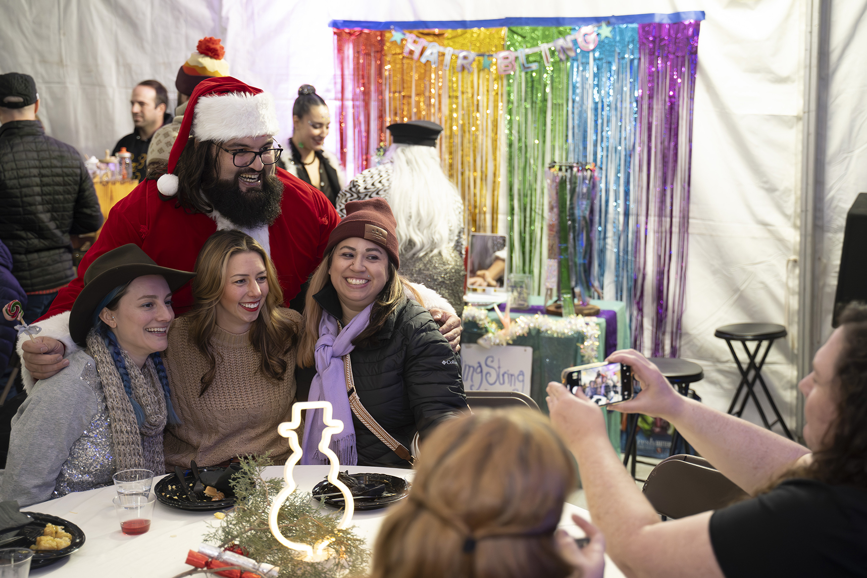 Group posing with Santa, rainbow backdrop says 