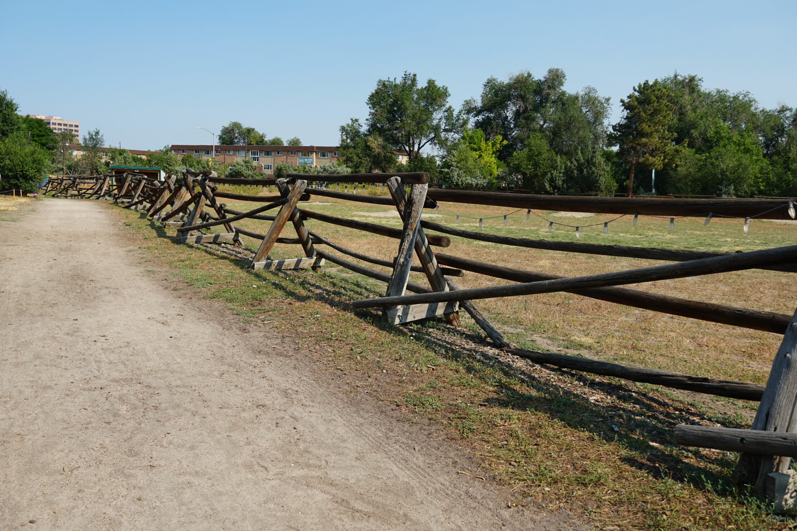 Dirt path lined with wooden fence line.