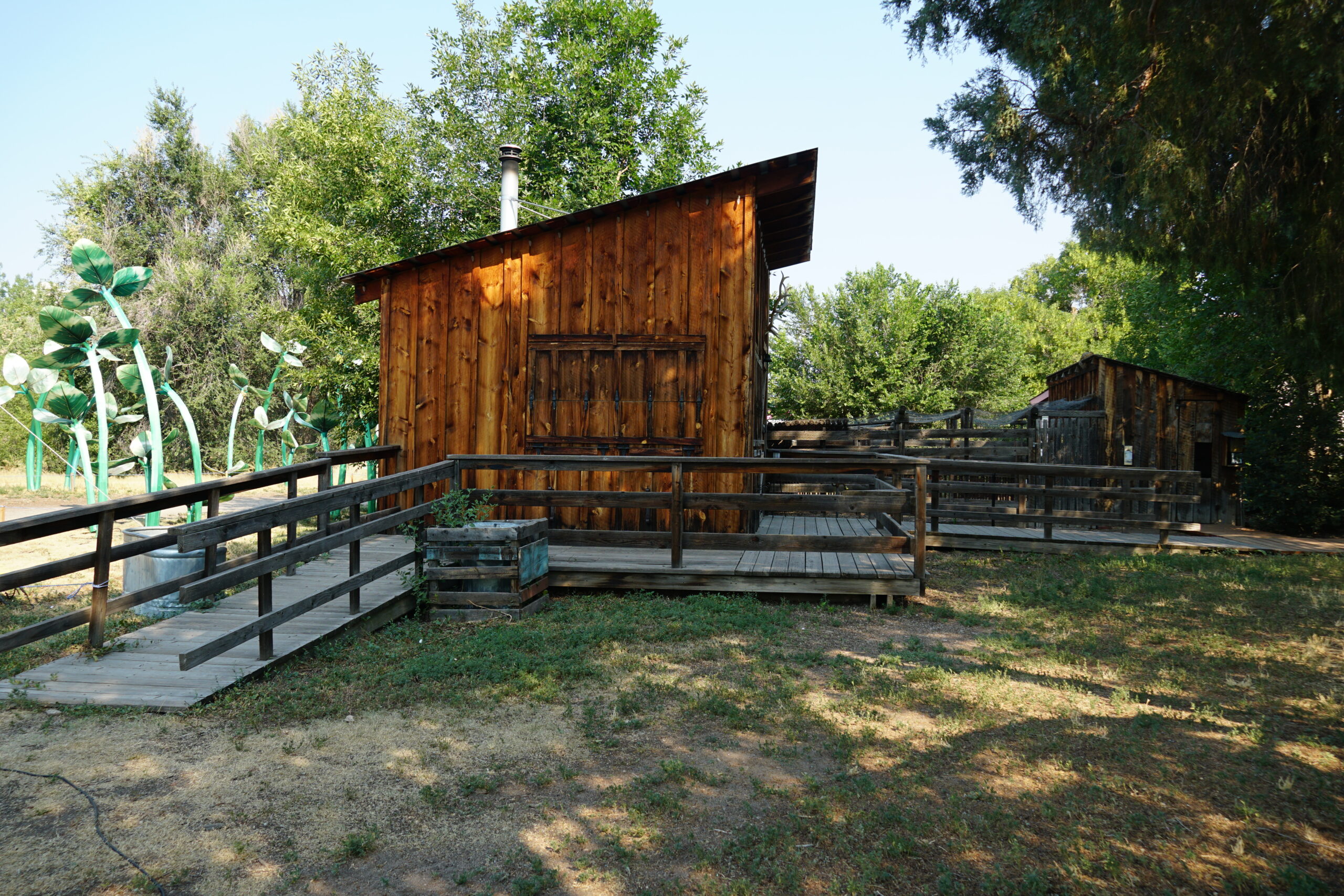 A wooden pathway with railings leads around two wooden buildings.
