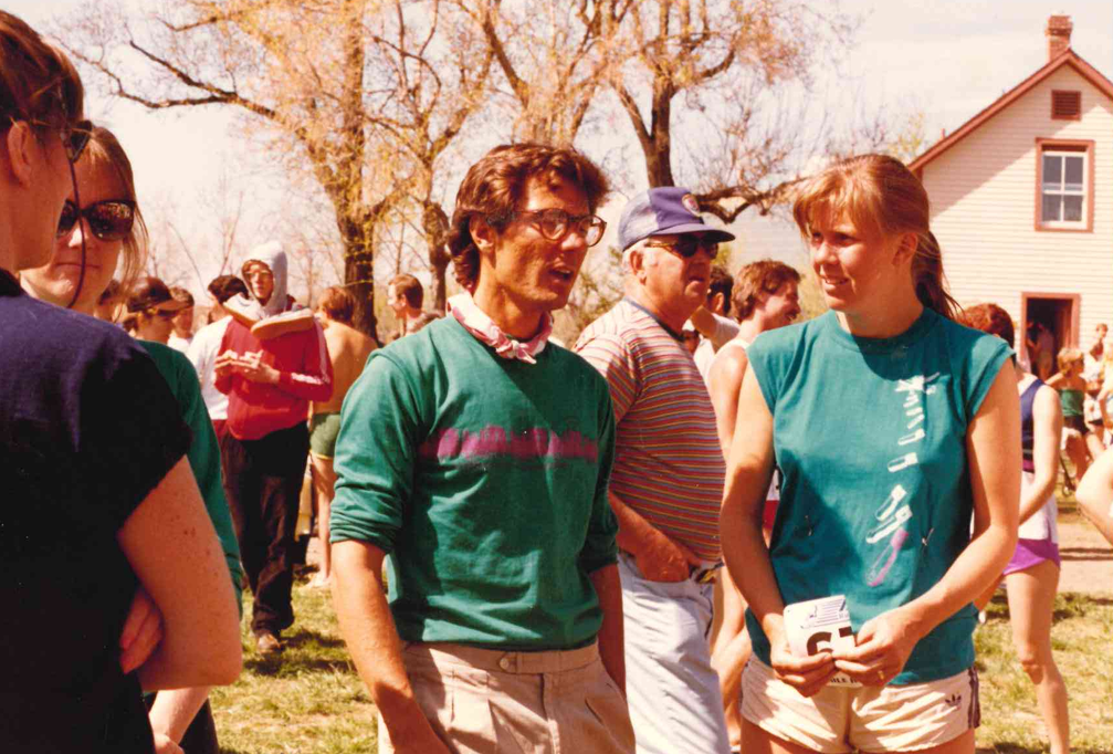 People conversing outdoors during a sunny event, with a house in the background