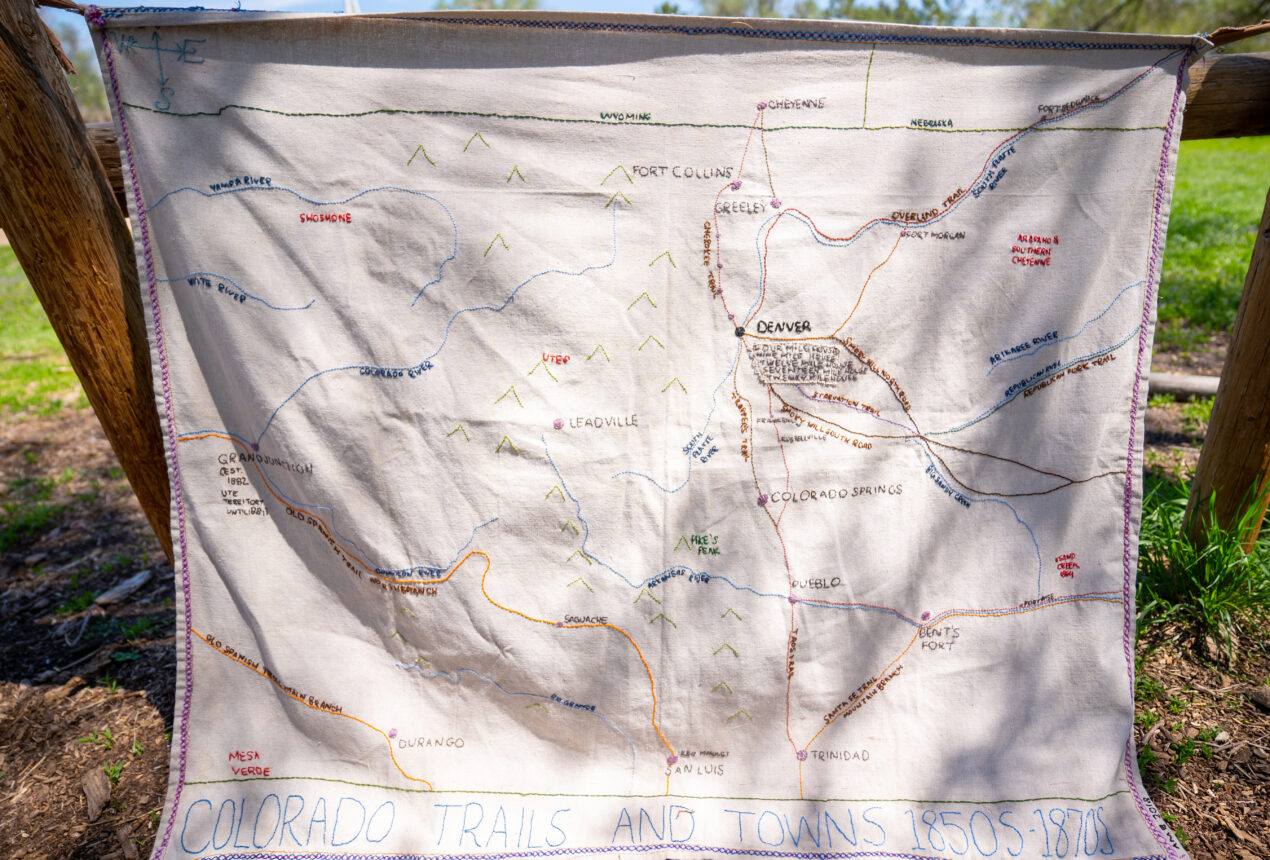 Embroidered map of Colorado trails and towns, 1850s-1870s, displayed outdoors