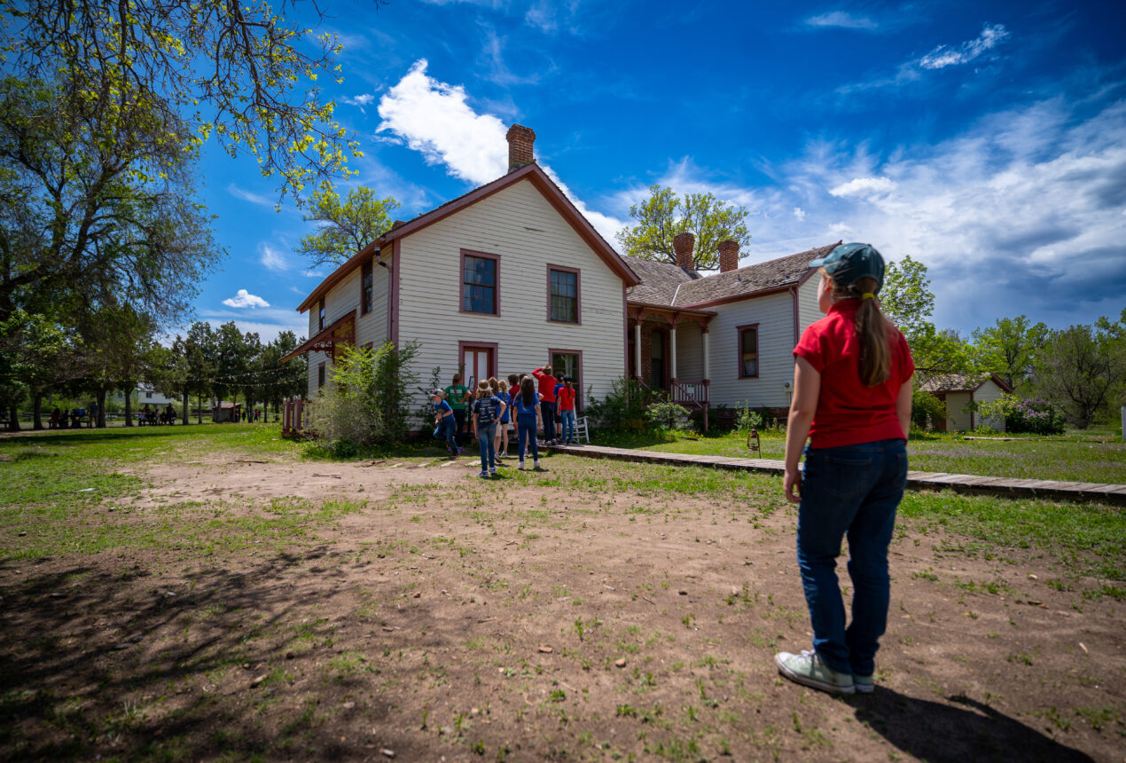 Group standing outside historical house under bright blue sky