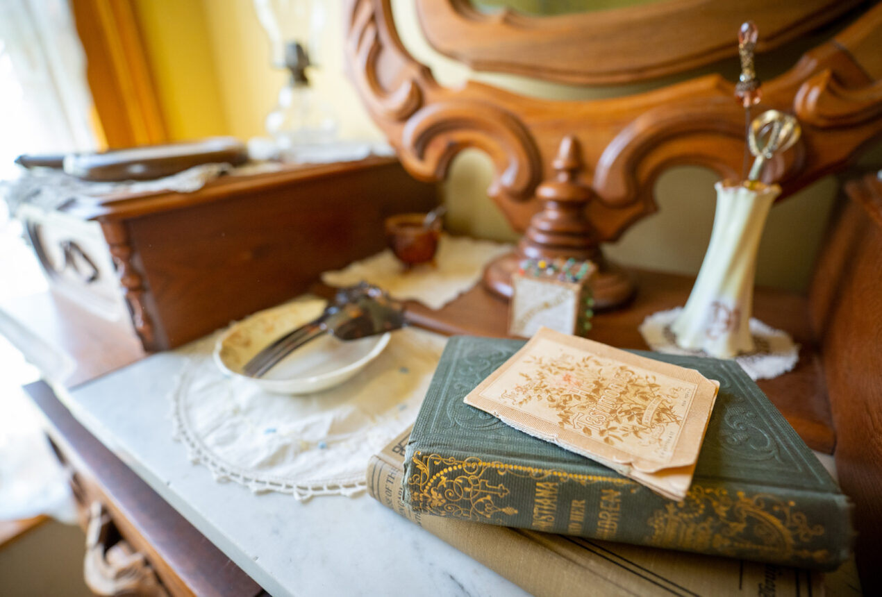 Antique dresser with mirror, book, paper, and decorative items, conveying a vintage ambiance