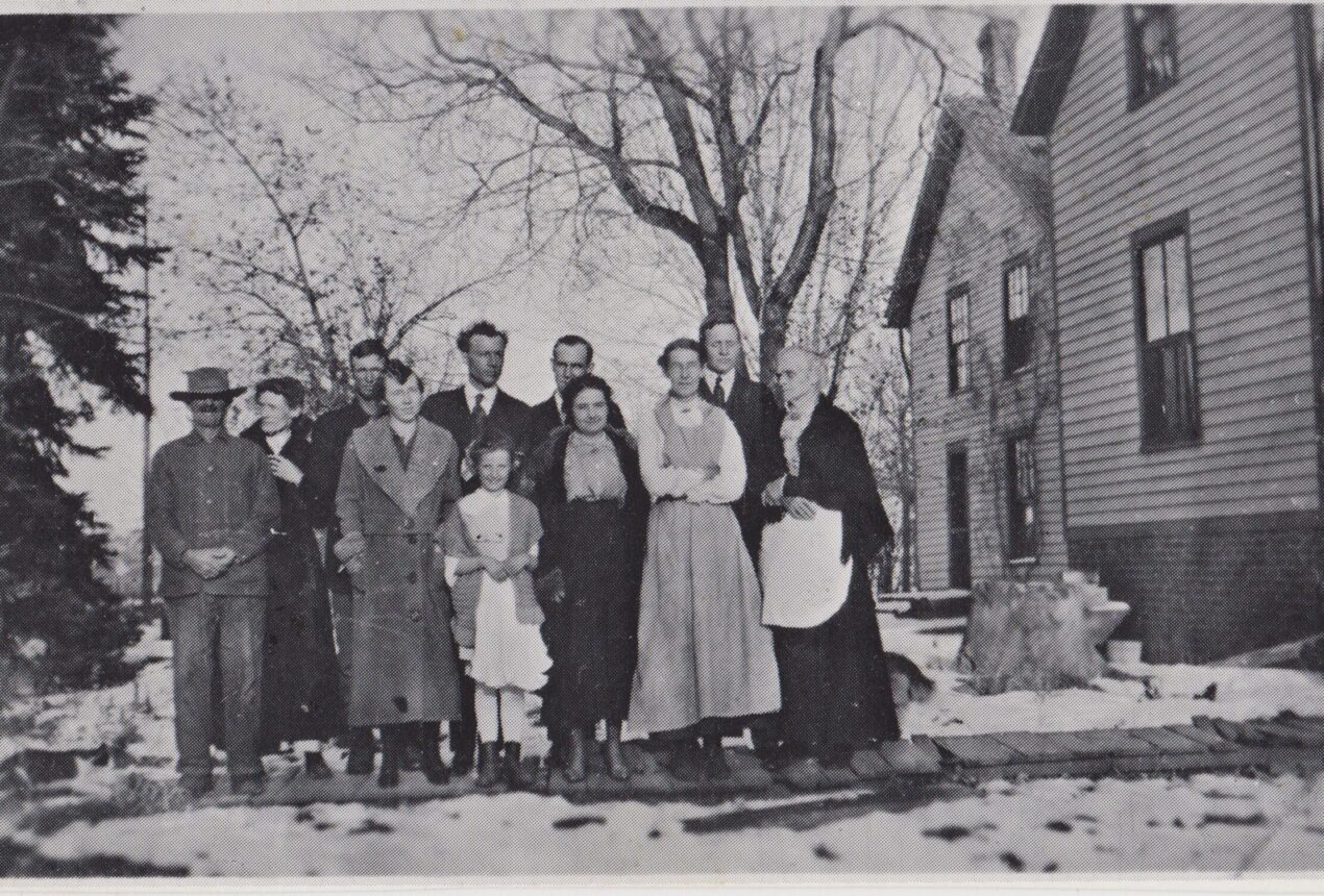 Early 1900s family posed outside a house in winter setting