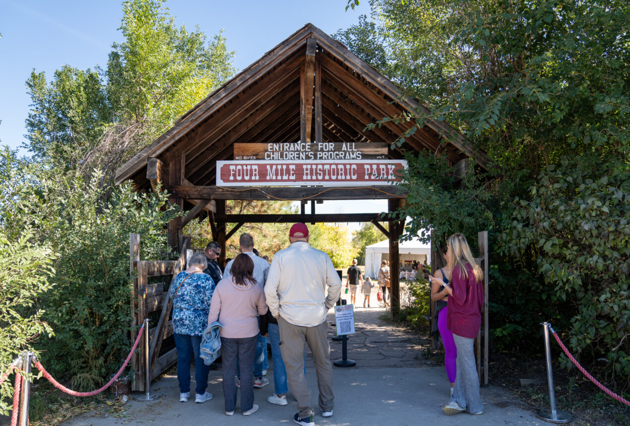 People entering Four Mile Historic Park, sign reads "Entrance for all children's programs."